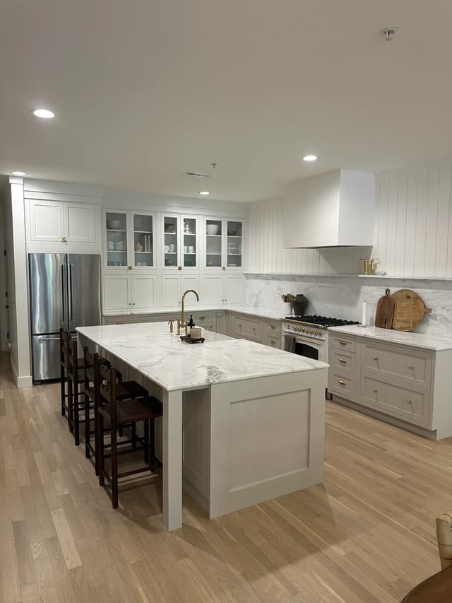 Coastal kitchen with soft greige cabinetry, white uppers, and brass hardware