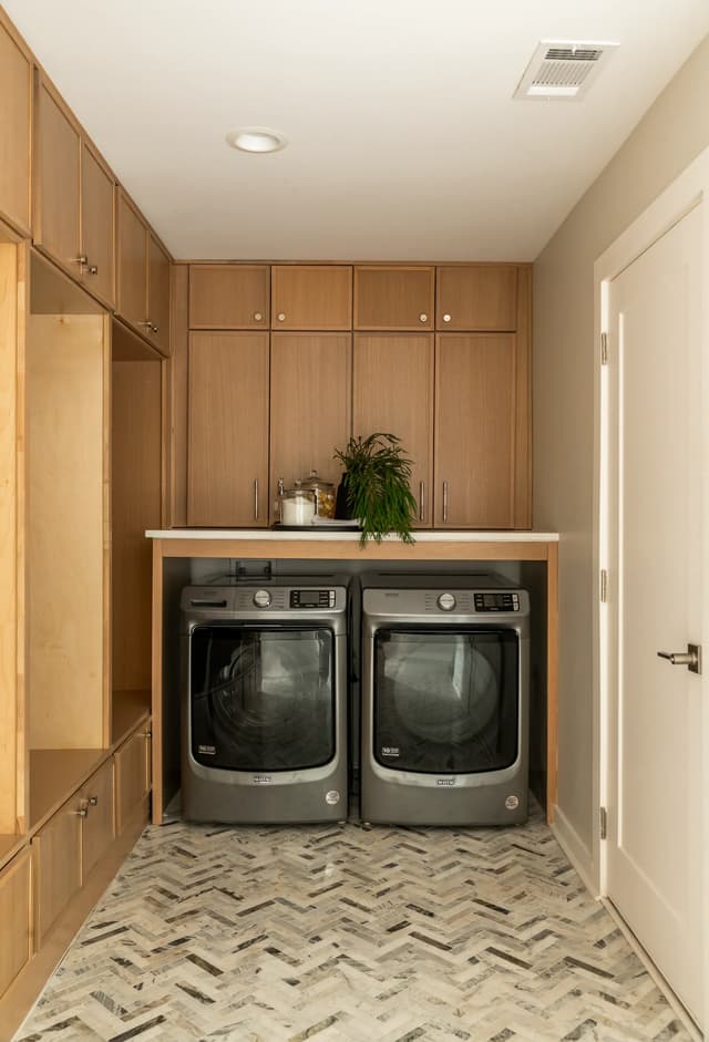 Natural oak laundry cabinetry and stone herringbone floor
