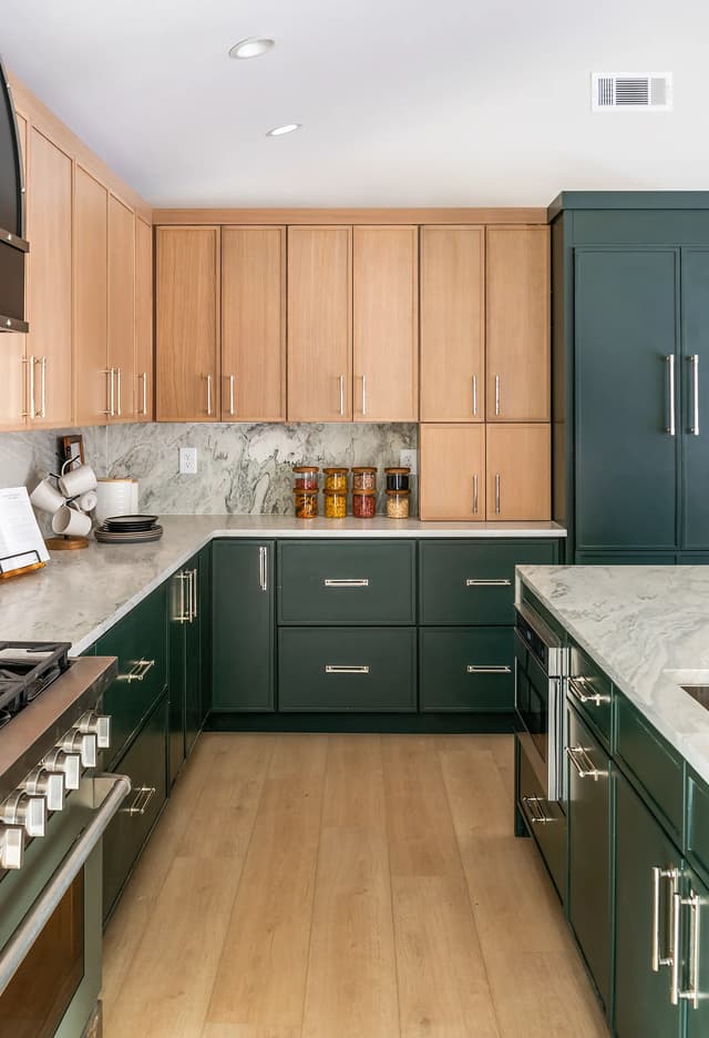 Natural oak upper cabinets paired with emerald base cabinetry