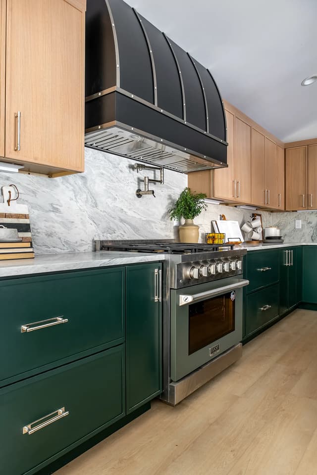 Detailed view of the black metal range hood and green base cabinetry