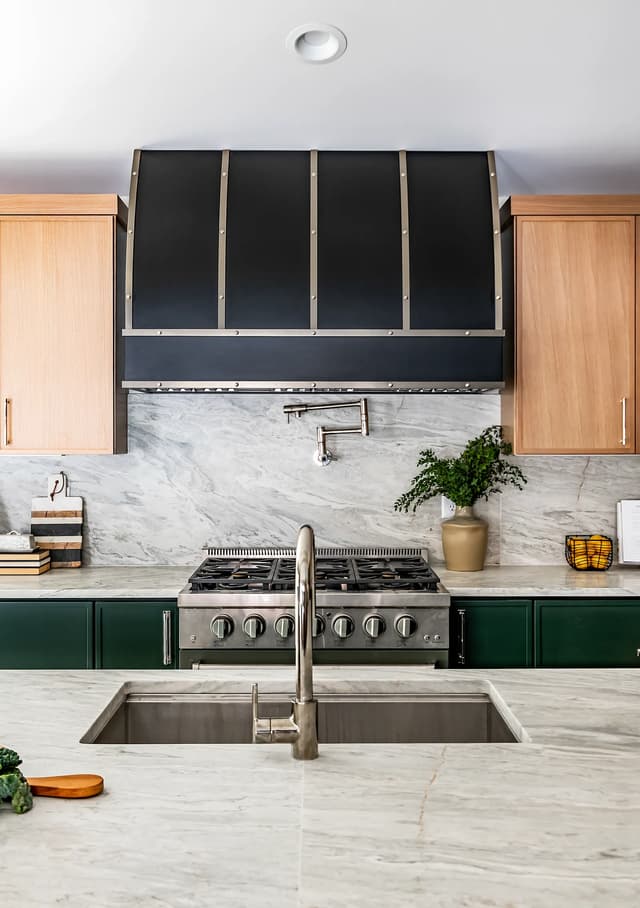 Emerald and natural oak kitchen centered on a tailored black range hood
