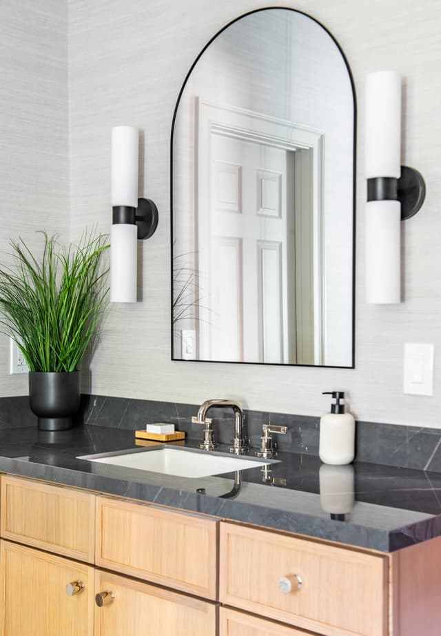Natural oak bath vanity, dark stone, and arched mirror detail