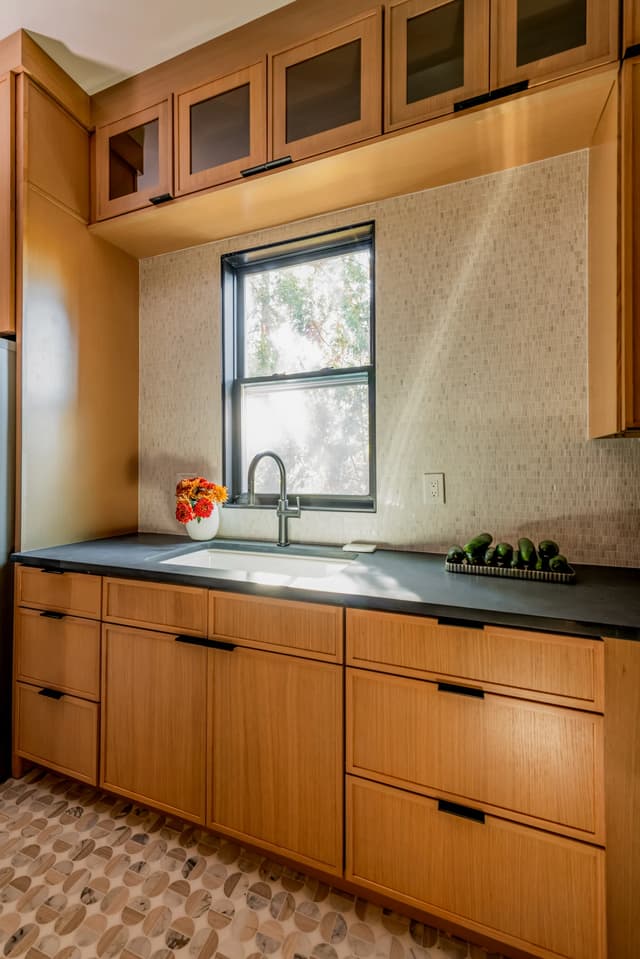 Pantry sink framed by natural oak cabinetry and a softly tiled wall