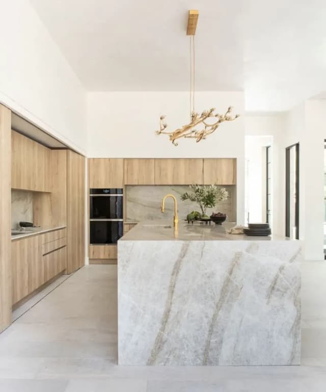Light oak kitchen with a dramatic waterfall stone island
