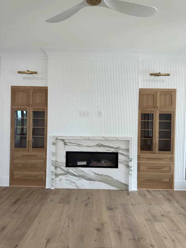 Warm oak built-ins framing an Italian marble fireplace