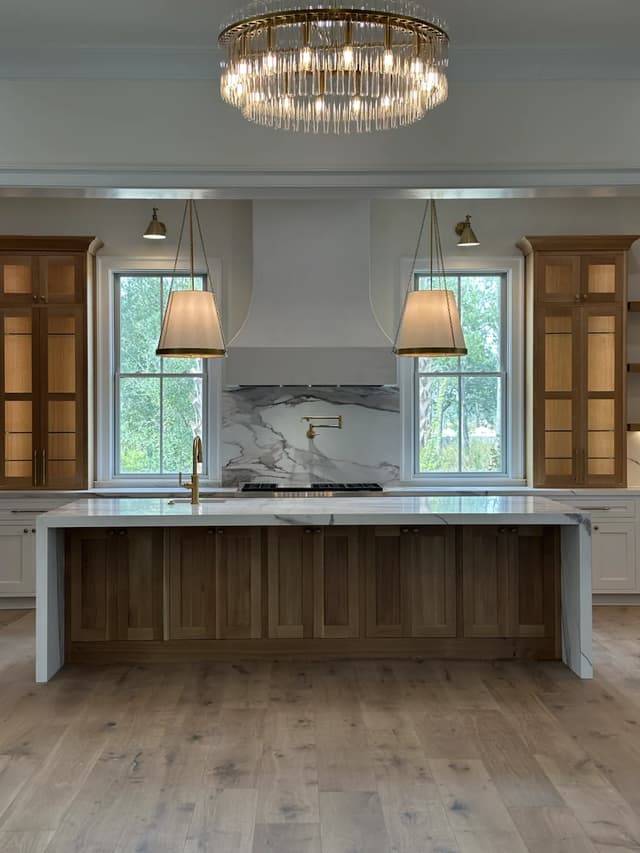 Warm oak towers framing the Italian marble range wall